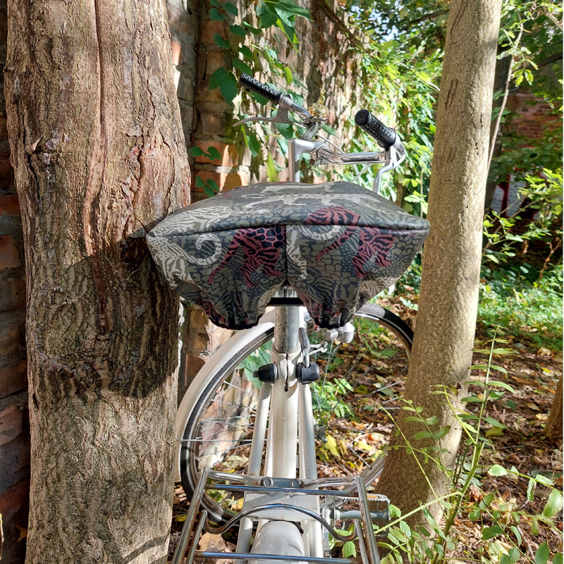 Ikuri Sattelschoner Animals auf einem Fahrradsattel vor einem Baum
