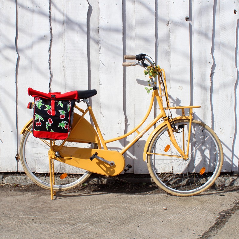 Gelbes Fahrrad mit Seitentasche Cerezas schwarz vor einer Wand