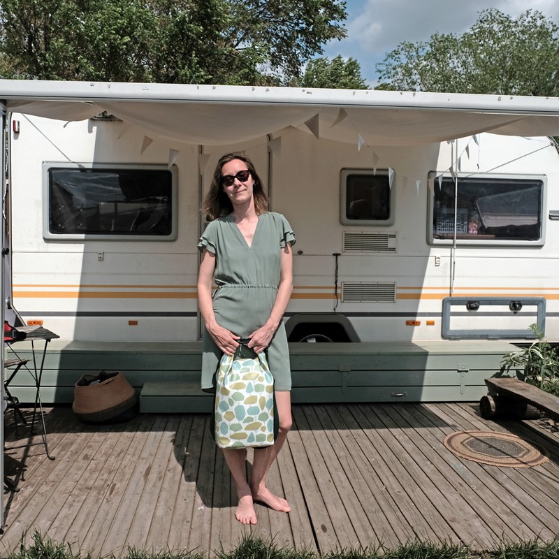 Frau hält den Drybag Bosque vor einem Wohnwagen auf dem Campingplatz