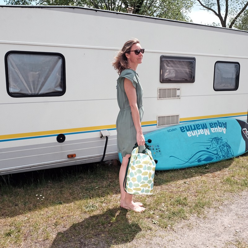 Frau mit wasserdichtem Rucksack Bosque neben Wohnwagen und SUP-Board