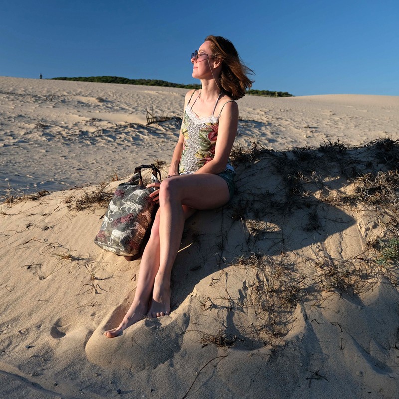 Frau sitzt in den Dünen, daneben der Drybag Animals
