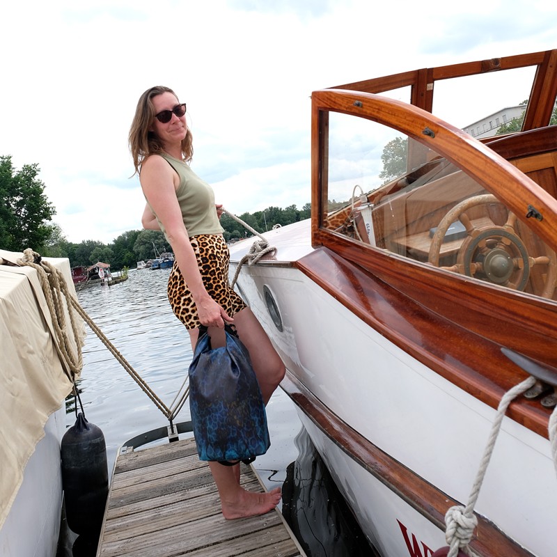 Frau mit wasserdichtem Rucksack Pantera neben einem Holzboot