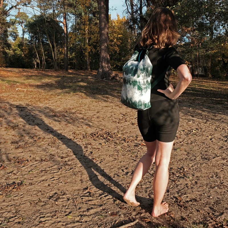 Frau trägt den Drybag Pinos als Rucksack am Sandstrand im Wald