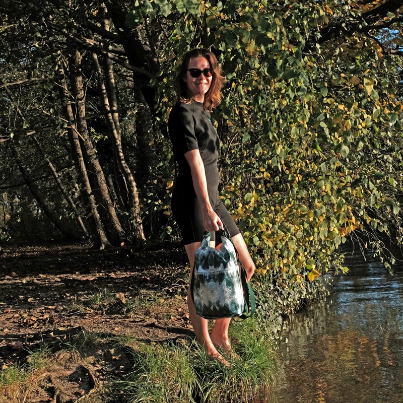 Frau hält den Drybag Pinos am Ufer eines Waldsees