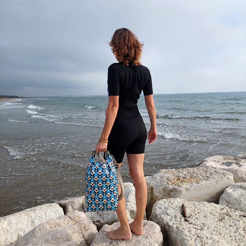 Frau hält den Drybag Scandinavia in der Hand an der Küste