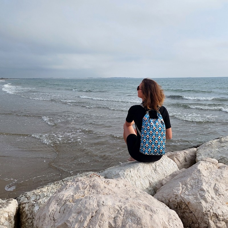 Frau mit Drybag Scandinavia auf dem Rücken blickt aufs Meer