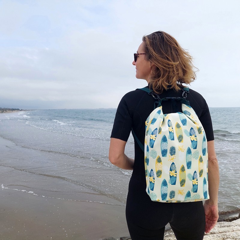 Frau trägt den Drybag Surf als Rucksack am Strand