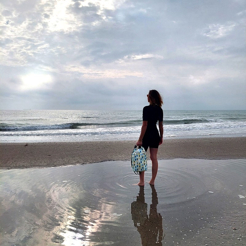Frau hält den Drybag Surf am Meeresufer bei Ebbe