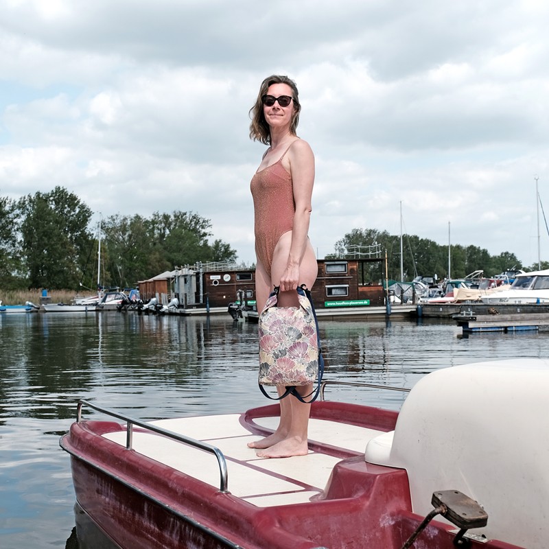 Frau steht mit dem wasserdichten Rucksack Veranillo auf einem Tretboot