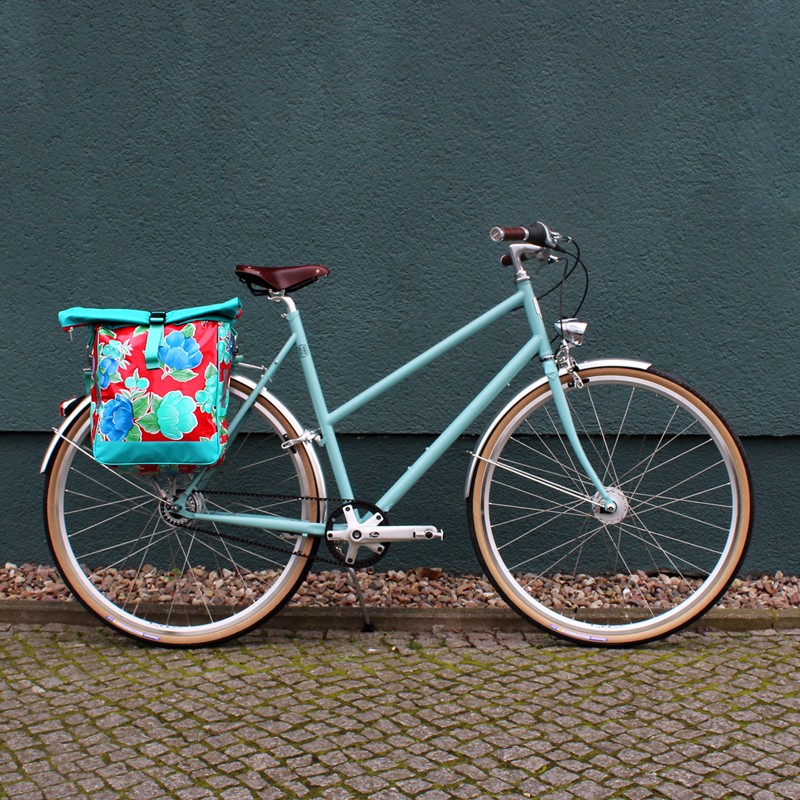 Fahrrad mit Seitentasche Capullo vor einer grünen Wand
