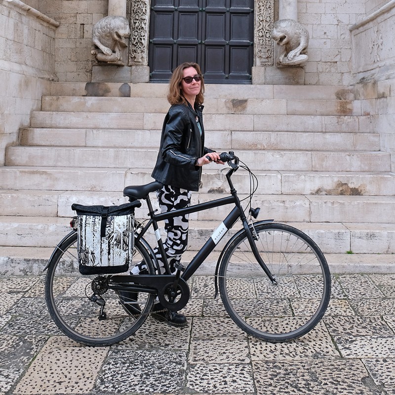 Frau mit Fahrrad und Seitentasche Palmeras vor einer Kirche