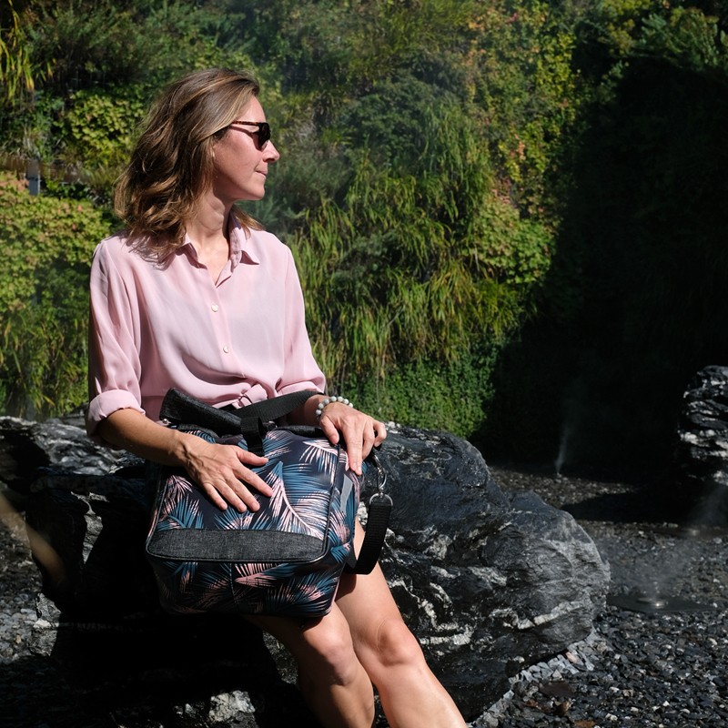 Frau sitzt an einem Wasserfall mit der Umhängetasche Retro Palma