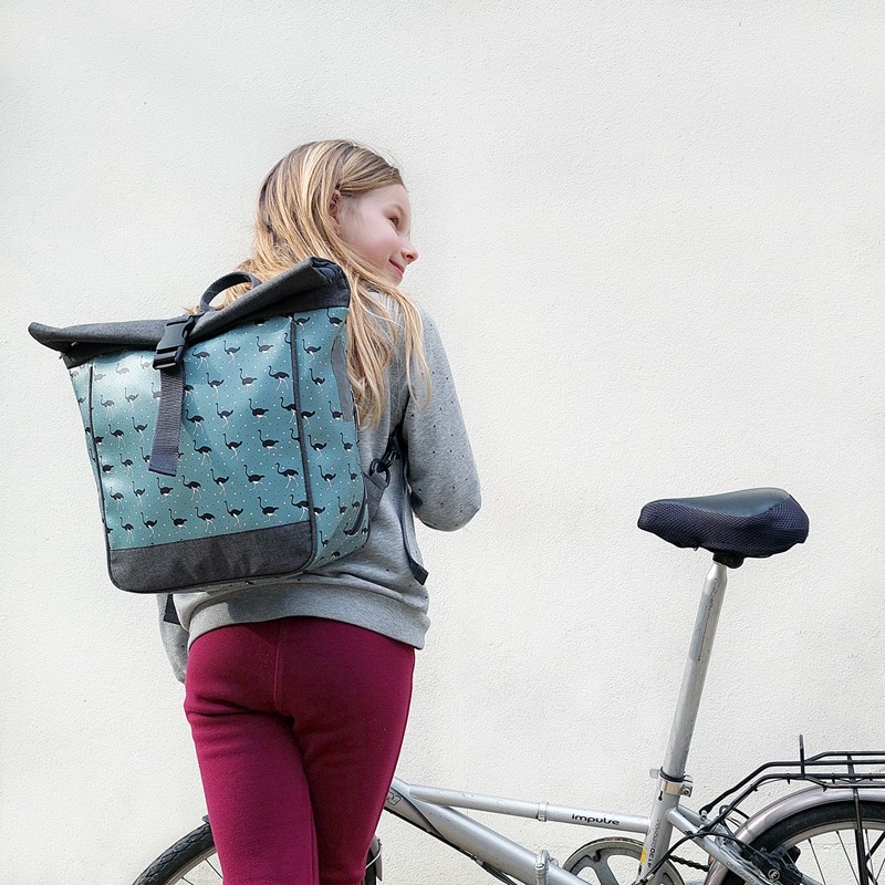 Mädchen trägt den kleinen Rucksack Avestruz von Ikuri neben einem Klapprad
