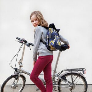 Mädchen trägt den kleinen Rucksack Azucena von Ikuri neben einem Klapprad