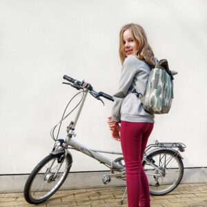 Mädchen trägt den kleinen Rucksack Banana Leaf von Ikuri neben einem Klapprad