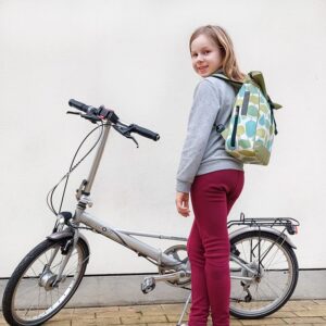 Mädchen trägt den kleinen Rucksack Bosque von Ikuri neben einem Klapprad