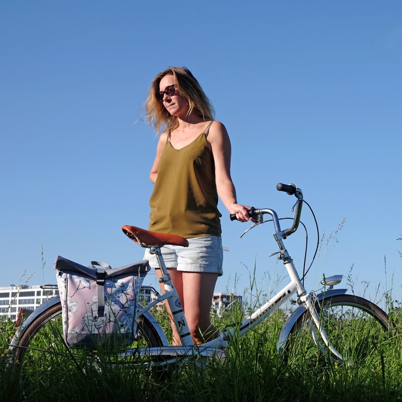 Frau mit kleinem Rucksack Magnolia am Fahrrad im Grünen