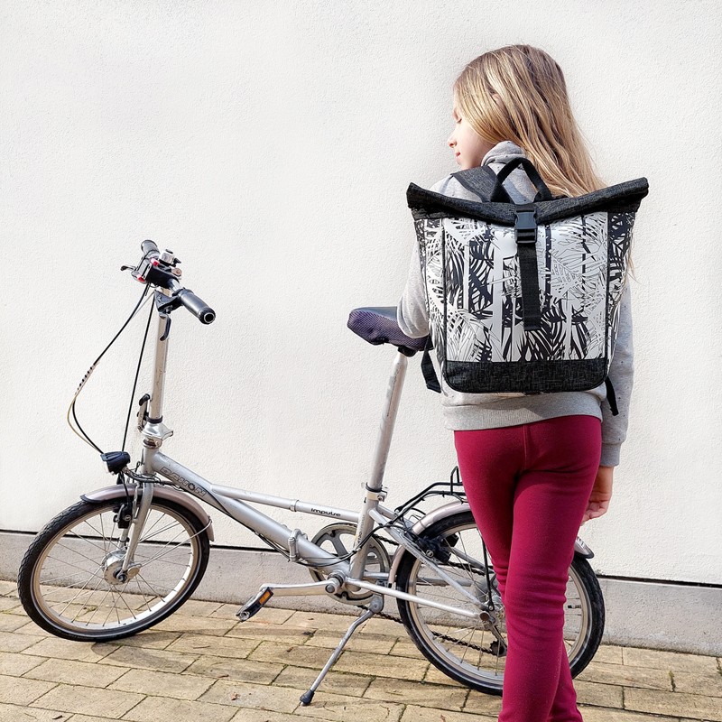 Mädchen trägt den kleinen Rucksack Palmeras von Ikuri neben einem Klapprad