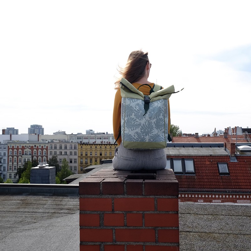Frau sitzt mit dem Fahrradrucksack Damen Monstera auf einem Dach über der Stadt