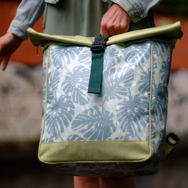 Frau hält den Rucksack Monstera in Hellgrün vor sich
