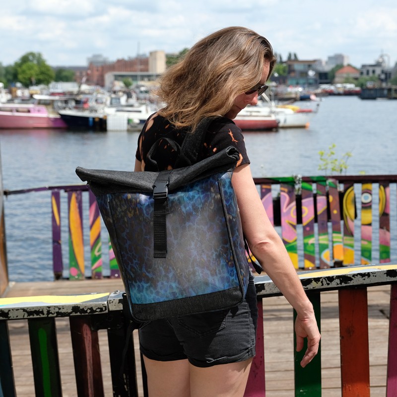 Rolltop-Rucksack Pantera mit blauem Muster, getragen von einer Frau am Hafen