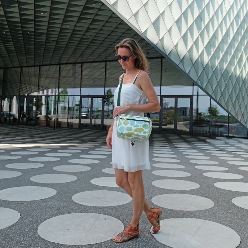 Frau trägt die Lenkerhandtasche Bosque vor moderner Architektur