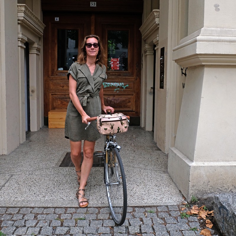 Frau mit Fahrrad und Lenkertasche Cactus in einer Toreinfahrt