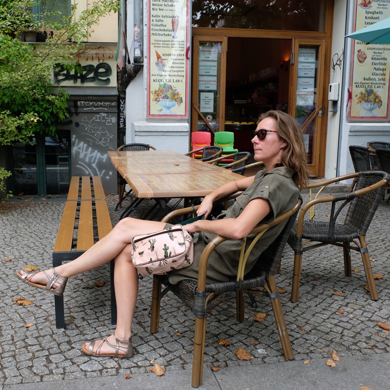 Frau sitzt im Café, daneben die Handtasche Cactus