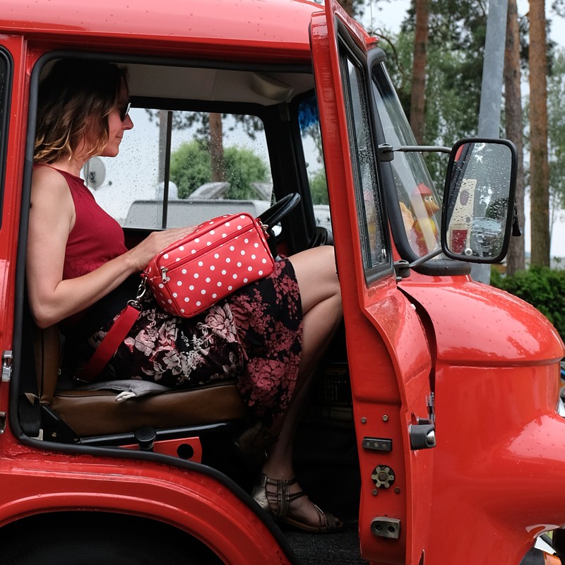 Frau mit Handtasche Lunares rot in einem roten Oldtimer