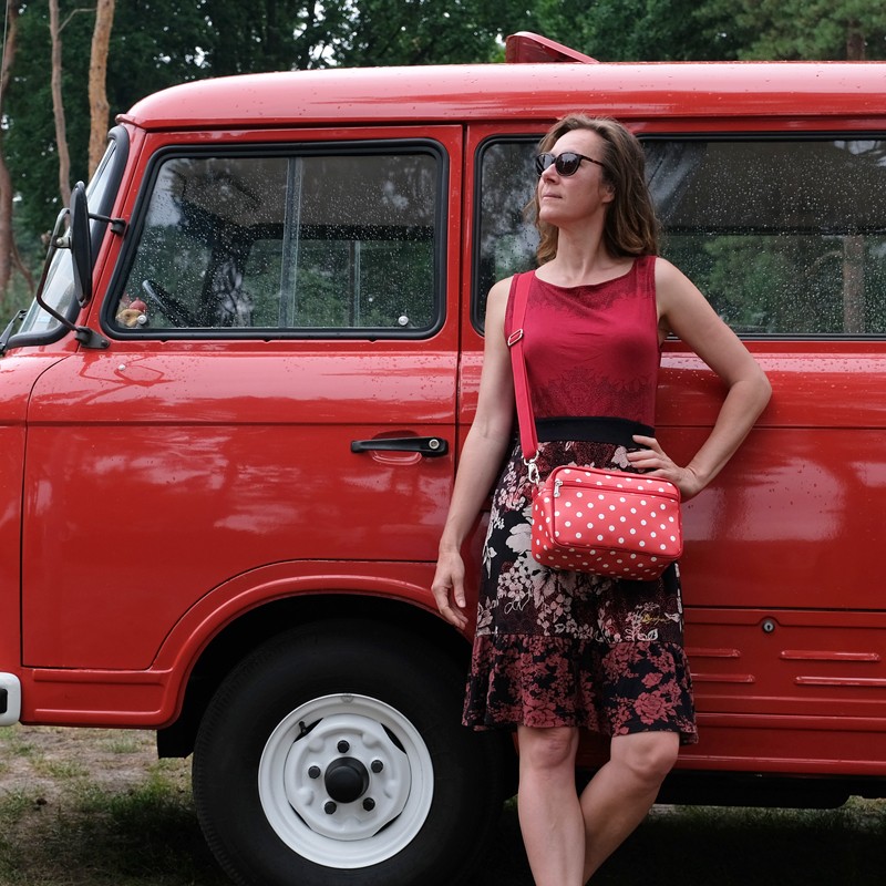 Frau mit Umhängetasche Lunares rot vor einem roten Oldtimer