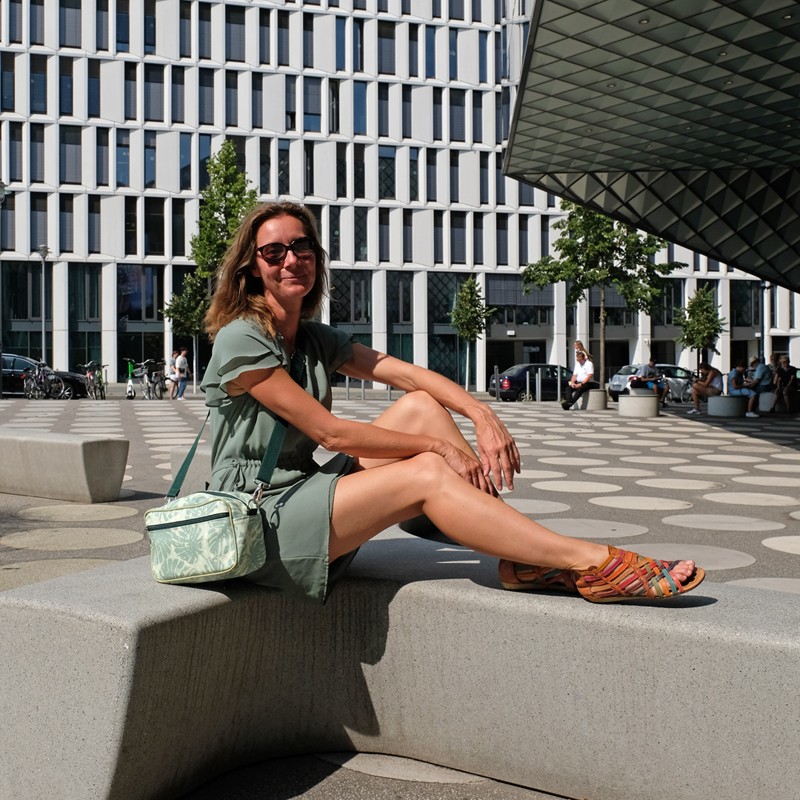 Frau sitzt mit der Handtasche Monstera auf einer Treppe