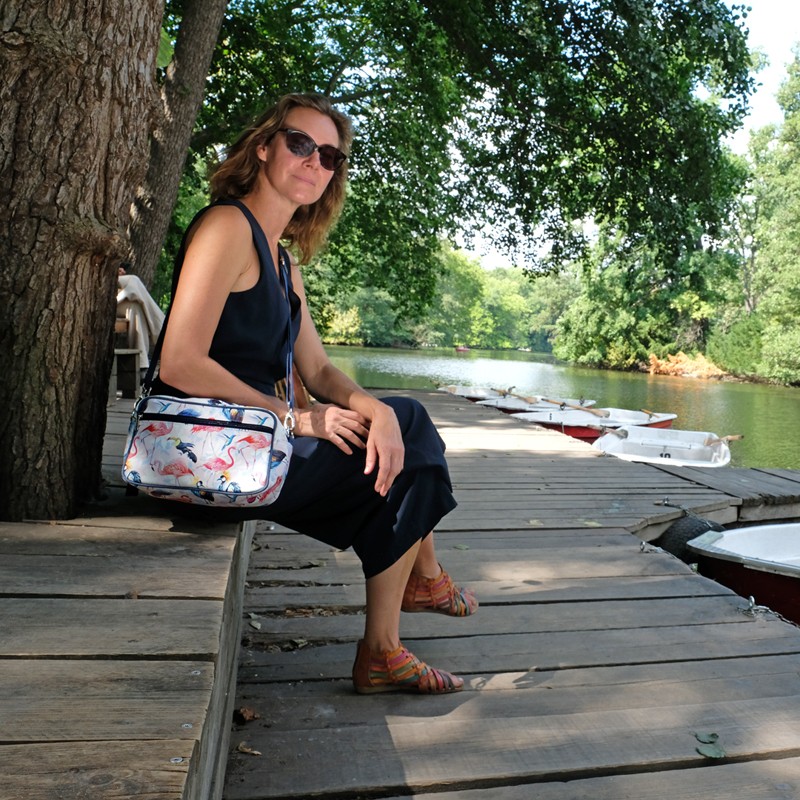 Frau sitzt am Wasser mit der Handtasche Pajaros