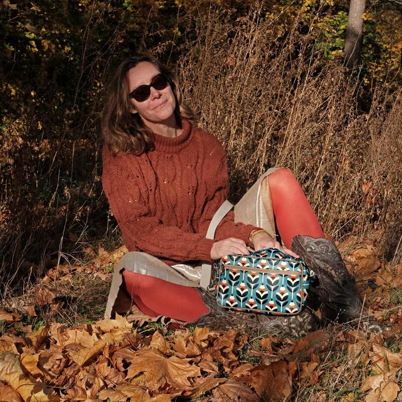 Frau sitzt im Herbstlaub mit der Handtasche Scandinavia