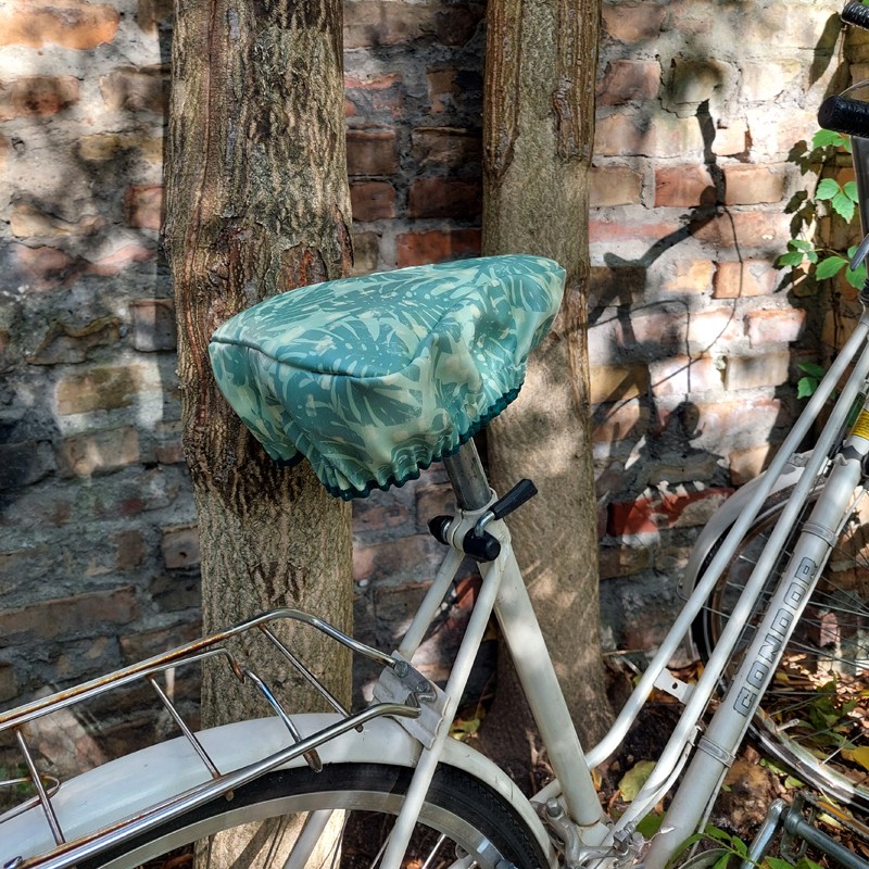 Ikuri Sattelschoner Monstera auf einem Fahrradsattel vor einem Baum