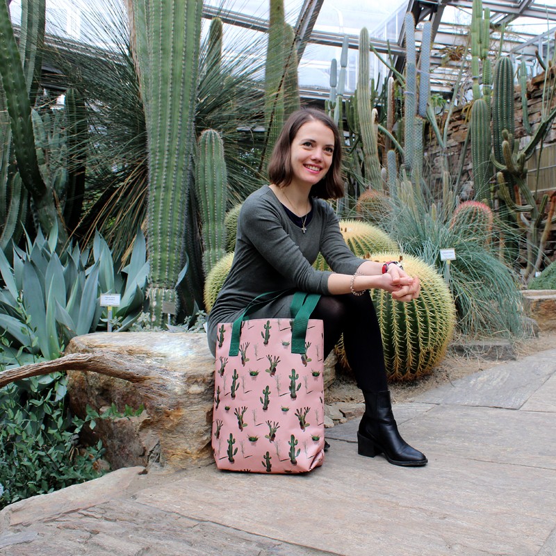 Frau sitzt im Kakteenhaus mit dem Shopper Cactus