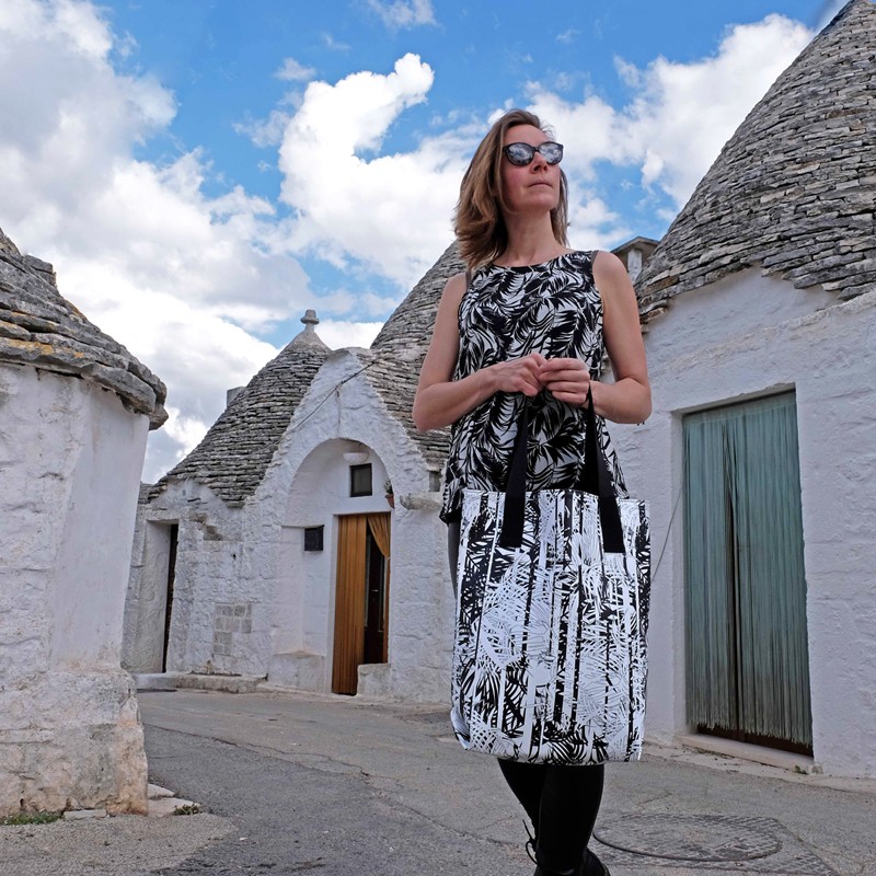 Frau trägt den Shopper Palmeras vor Trulli-Häusern